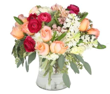 Premium garden flowers in shades of peach, blush, white, and bold magenta are designed gracefully in a clear glass vase and accented with premium greenery for a truly elegant show. 